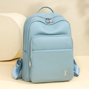 Detail view of light blue lychee pattern leather backpack with bunny icon and dual zippers