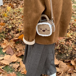 Détail d'un sac bandoulière en daim marron avec bordure en polaire et broderie d'ours
