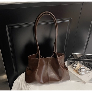 Close-up of deep brown pleated tote bag with smooth texture and soft shoulder straps