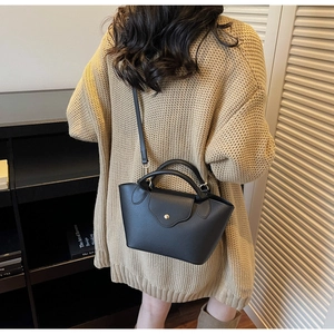 Detail view of black litchi grain leather bucket bag with gold circular buckle