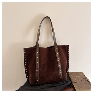 Close-up of vintage brown suede tote bag featuring vertical rivet details and soft texture
