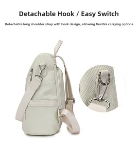 Detail view of the detachable shoulder strap with silver metal hook on beige backpack
