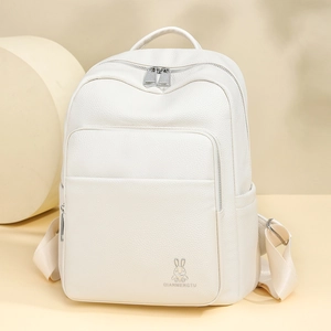 Detail view of cream white pebbled leather backpack with rabbit logo and silver zippers