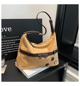 Detail of yellow suede hobo bag featuring brown leather straps and star patch accents