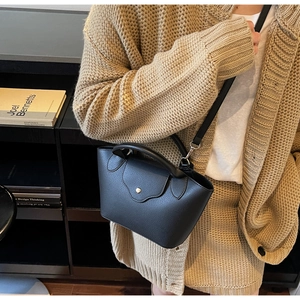 Detail of black mini bucket bag with lychee grain leather and golden buckle closure