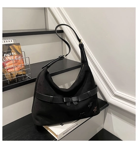 Detail view of black suede half-moon tote bag with star appliques and decorative bow