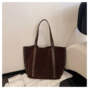 Detail of silver rivets on dark brown suede tote bag with metallic stud accents