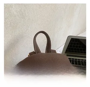 Macro view of brown vintage backpack featuring top handle and gold zipper detailing