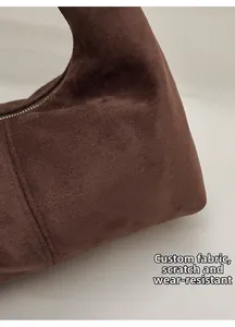 Close-up of premium brown suede dumpling bag featuring silver metal zipper and soft texture