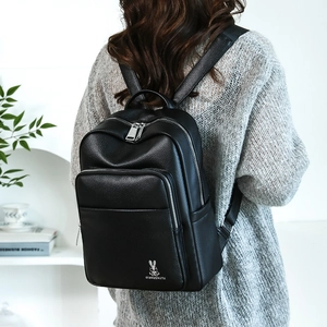 Detailed back view of a black lychee texture leather backpack worn by a model