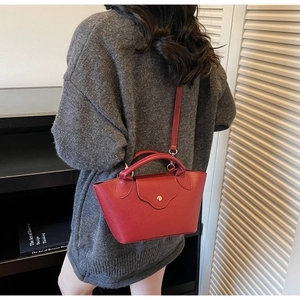 Detail of red bucket bag with litchi texture leather and golden magnetic buckle