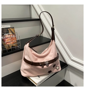 Detail of pink hobo shoulder bag with brown bow strap and star patches on a staircase