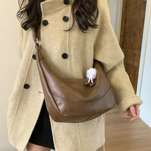 Detail view of a brown faux leather hobo bag with adjustable strap and plush pendant