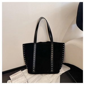 Detailed view of black suede tote bag with silver metal studs and leather handles
