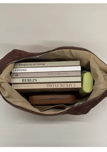 Spacious interior of brown suede hobo bag showing books and umbrella storage