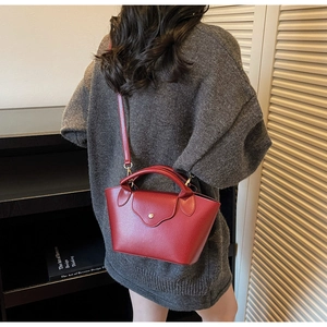 Detailed view of red lychee pattern leather handbag with gold metal clasp on a model
