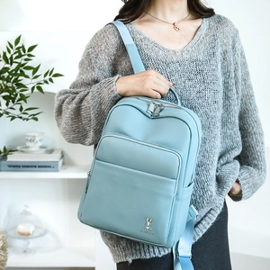 Close-up of a sky blue backpack featuring a rabbit metal logo and litchi texture finish