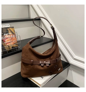 Close-up of retro brown suede hobo bag with delicate bow knot and star ornaments