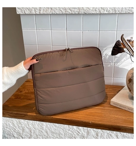 Close-up of brown quilted laptop sleeve with glossy finish and dual zipper closure