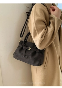 Detailed view of retro pebbled leather handbag featuring metal buckle and adjustable strap
