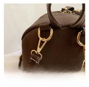 Detail of dark brown matte leather bag with high-quality gold hardware and lobster clasp