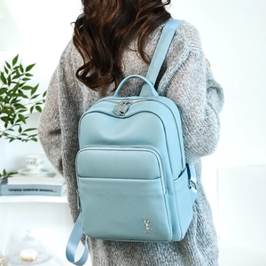 Detail of light blue textured leather backpack with metal rabbit logo and silver hardware