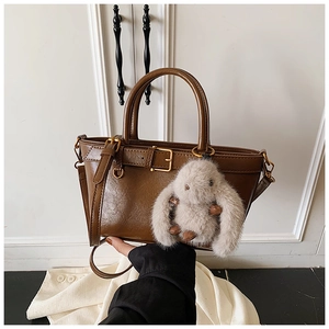 Detail of vintage brown leather handbag with buckle strap and plush bunny charm