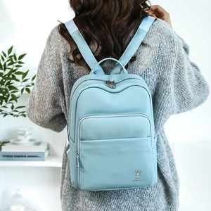 Close-up of light blue pebbled leather backpack with silver rabbit logo on model