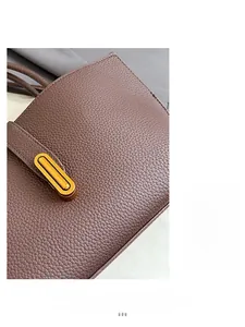 Detail view of brown lychee grain leather texture and gold oval twist lock on a bucket bag