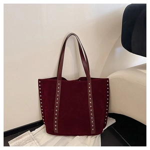 Detail of silver rivets on dark red suede tote bag with smooth leather strap