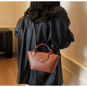 Detailed back view of a brown pebbled leather bucket bag styled with a black coat