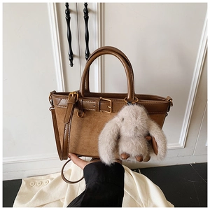 Detail of brown faux leather bucket bag with gold buckle and cute plush rabbit charm