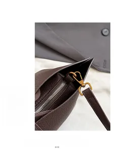 Macro detail of dark brown litchi grain leather bag with high-quality golden metal hardware