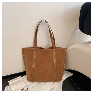 Detail view of large brown suede tote bag with stylish vertical silver rivets and smooth handles