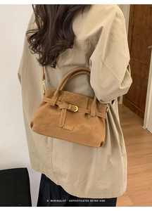 Close-up of brown suede hobo bag with belt buckle detail and minimalist embossed logo
