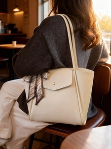 Chic cream leather tote bag with silk scarf in a cozy cafe setting, large capacity bag