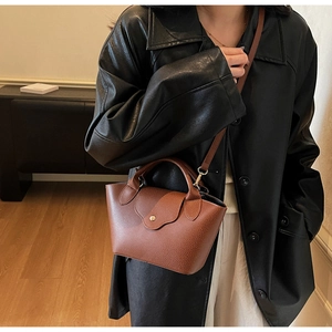 Detail shot of caramel lychee grain leather bucket bag with golden metallic snap button