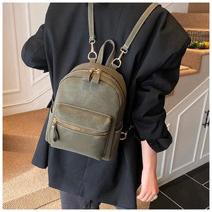 Détail d'un sac à dos vert olive avec coutures contrastées blanches et ferrures dorées