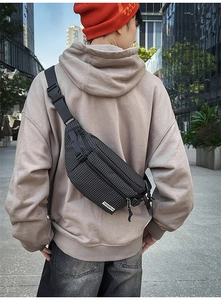 Rear view of a black and white checkered crossbody bag worn by a model in a city street