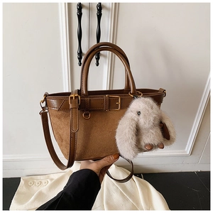 Detail of brown suede tote bag with leather straps and a cute plush rabbit charm