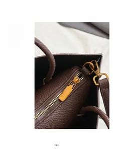 Detail of golden metal zipper and litchi grain dark brown leather on the tote bag