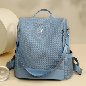 Detail of light blue backpack with woven texture and silver rabbit logo on front