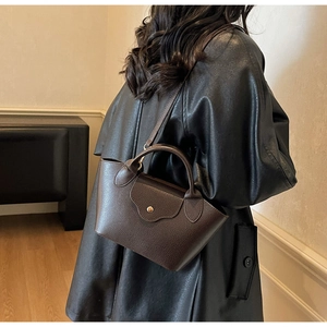 Dark brown leather bucket bag shown as a crossbody purse in a stylish indoor setting