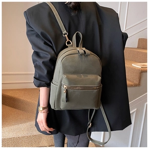 Détail d'un sac à dos vert olive avec surpiqûres sur escalier porté par un mannequin