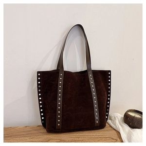 Close-up detail of silver rivets on a dark brown suede tote bag with long shoulder straps