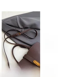 Detail of dark brown pebble leather handbag with gold metal accents and adjustable strap