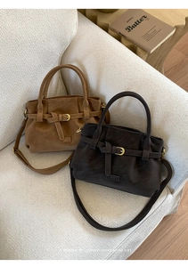 Close-up of retro caramel and coffee brown shoulder bags with buckle detail on a sofa