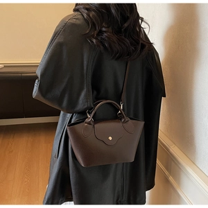 Detailed macro view of dark brown litchi pattern leather bucket bag with gold button
