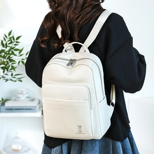 Rear view of a minimalist white leather backpack with metal zippers on a female model