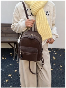 Détail du sac à dos en cuir marron foncé avec coutures blanches et zip doré élégant
